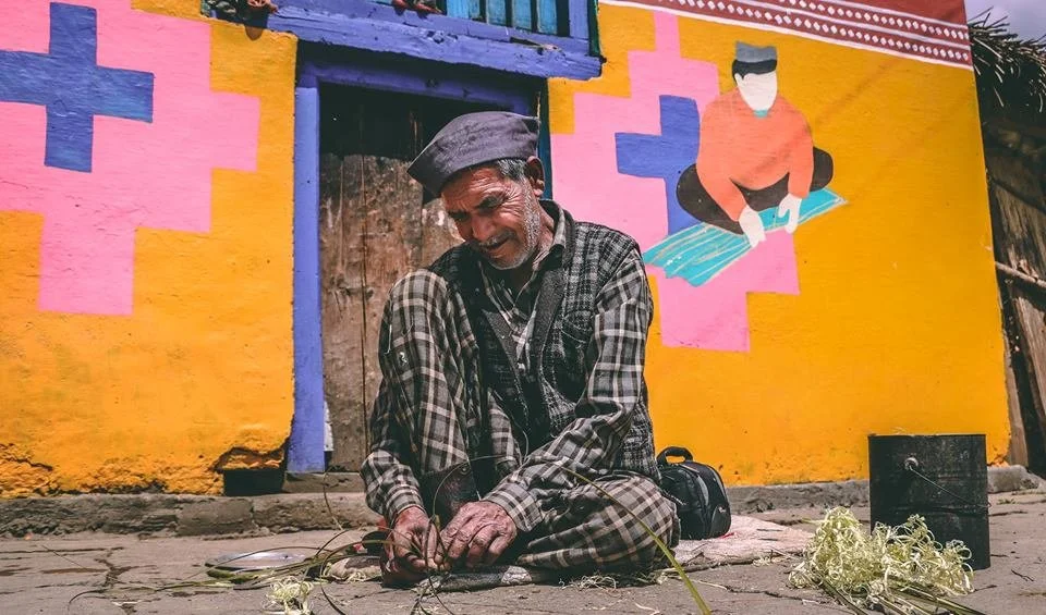 A village elder in front of a painted wall